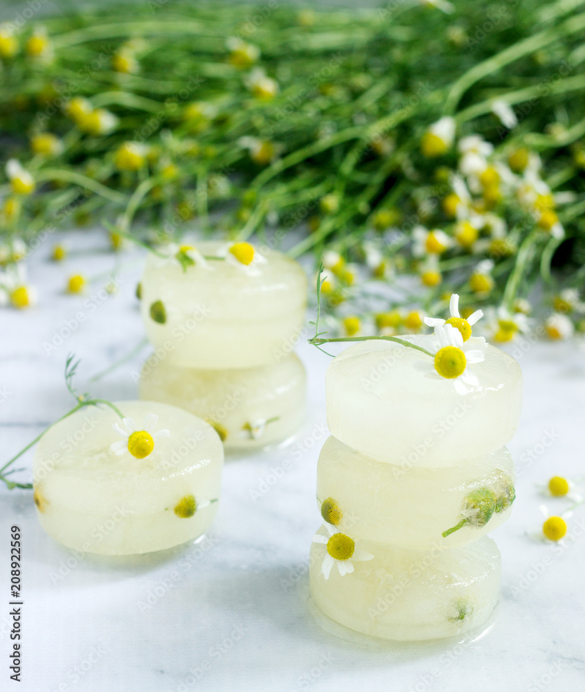 Ice cubes of chamomile tea and chamomile for cosmetic purposes on a background of a bouquet of daisies.