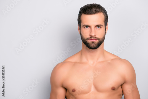 Portrait with copy space of thoughtful, concentrated, unshaven, naked man with perfect, ideal skin isolated on gray background