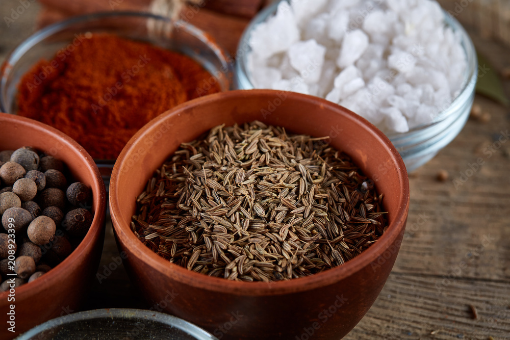 Spices in ceramic and glass bowls on the top of wooden barrel, close-up, selective focus. Spices in ceramic and glass bowls on the top of wooden barrel, close-up, selective focus.