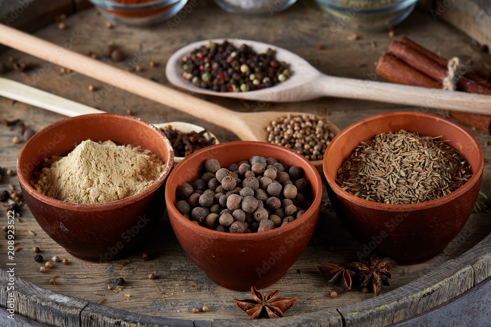 Various spices in wooden spoons and bowls on an old wooden barrel, top view, close-up, selective focus. Various spices in wooden spoons and bowls on an old wooden barrel, top view, close-up, selective focus.