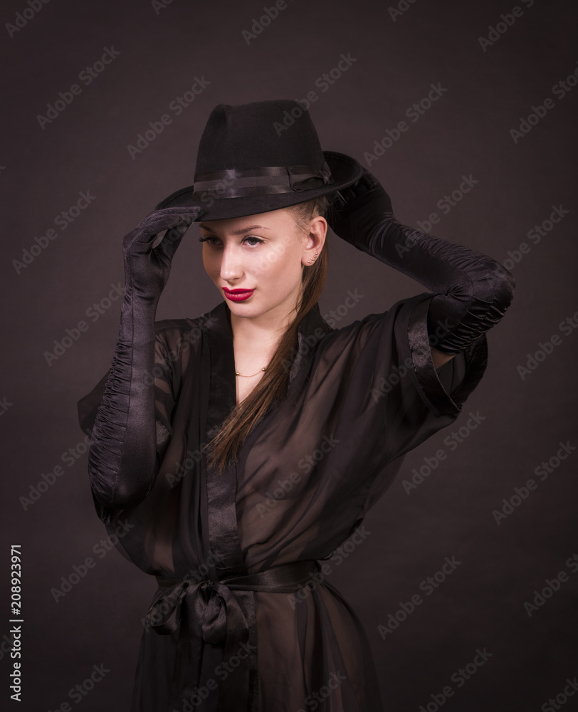 Beautiful young girl with long hair, black tunic, black gloves and black hat. Beautiful young girl with long hair, black tunic, black gloves and black hat.