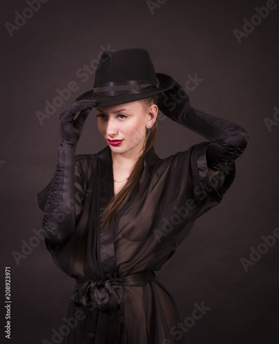 Beautiful young girl with long hair, black tunic, black gloves and black hat.