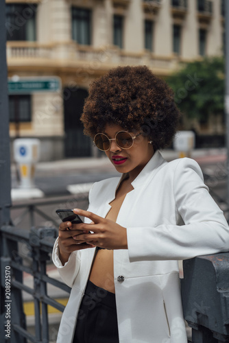 Beautiful Afro hair girl with mobile phone in the streets of Madrid Spain