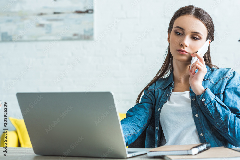 serious teenage girl talking by smartphone and using laptop at home serious teenage girl talking by smartphone and using laptop at home