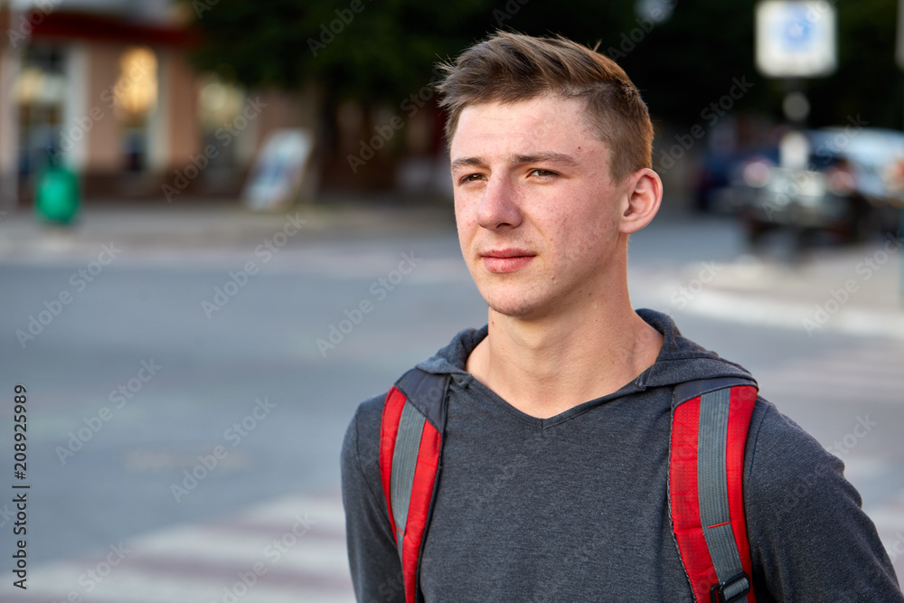 Fototapeta premium A young happy guy with problem skin having fun while walking around the summer city.