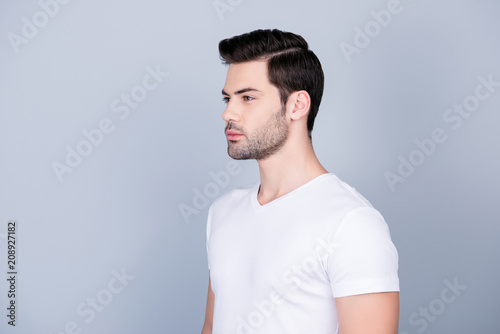 Portrait of half turned stunning man in white t-shirt with modern hairstyle soft smooth skin, isolated on grey background