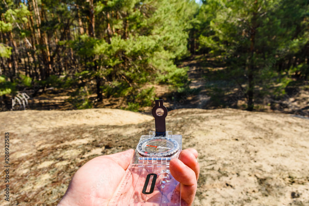 Traveler looking for the right way in a forest with compass