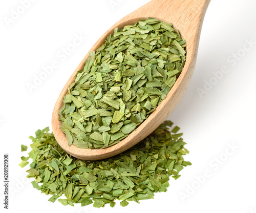 dried tarragon leaves in the wooden spoon, isolated on white