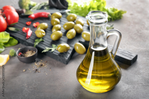 Glass jug with fresh olive oil on table