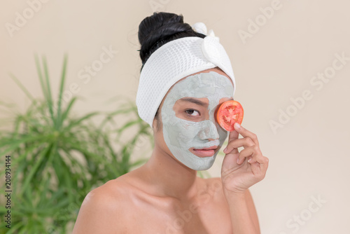  Young woman having clay facial mask in beauty salon