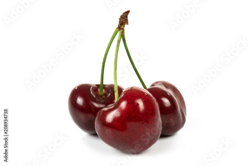 Three ripe perfect cherries isolated on a white background in close-up.