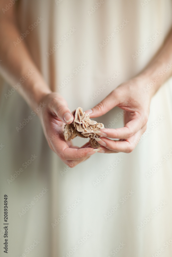 Woman hand holding little crystal mineral rock, sensual studio shot with soft light, can be used as background 