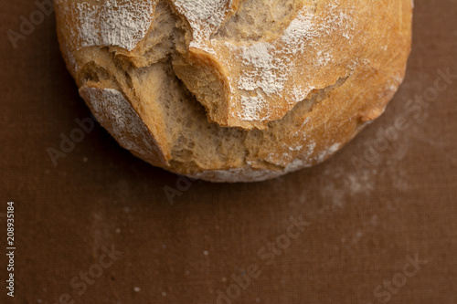 Top view for a crispy, golden, floured bread, baked on sourdough. Isolated place for text or subtitles. Round loaf of freshly backed bread, copy space