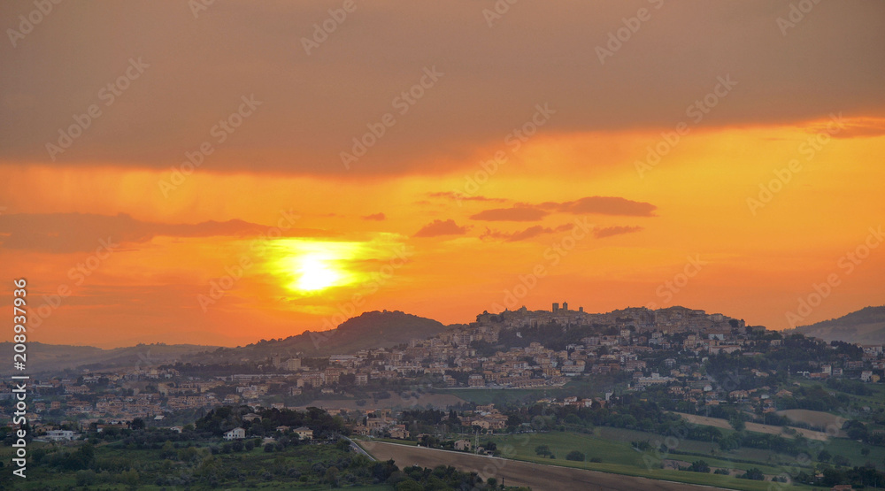 Fototapeta premium colorful warm sunset with little town Osimo on the green hills in Marche , Italy