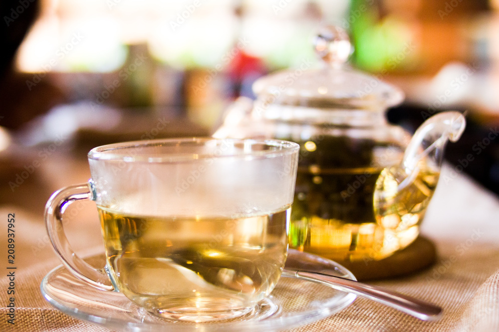 Beverages, good morning and breakfast concept - Cup of white green tea and teapot on the table Beverages, good morning and breakfast concept - Cup of white green tea and teapot on the table