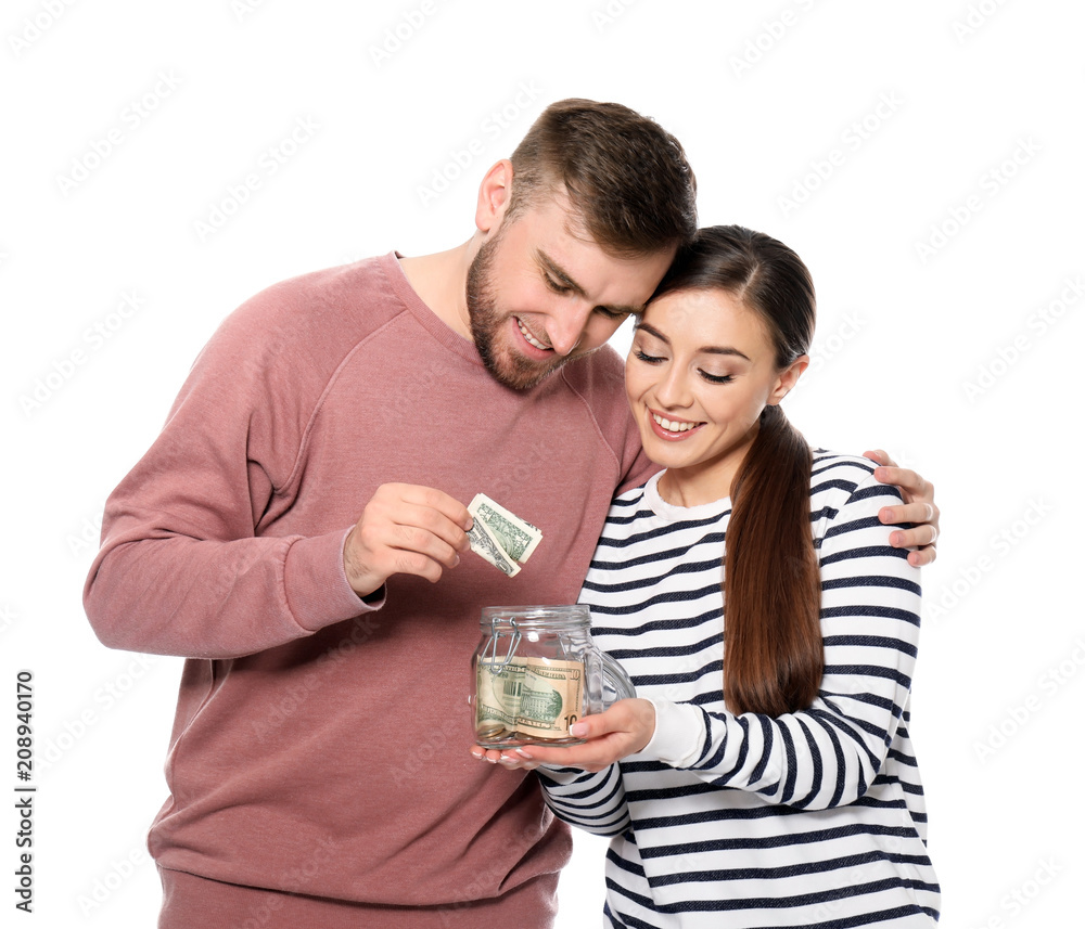 Happy couple putting dollar banknote into glass jar on white background. Money savings concept Happy couple putting dollar banknote into glass jar on white background. Money savings concept