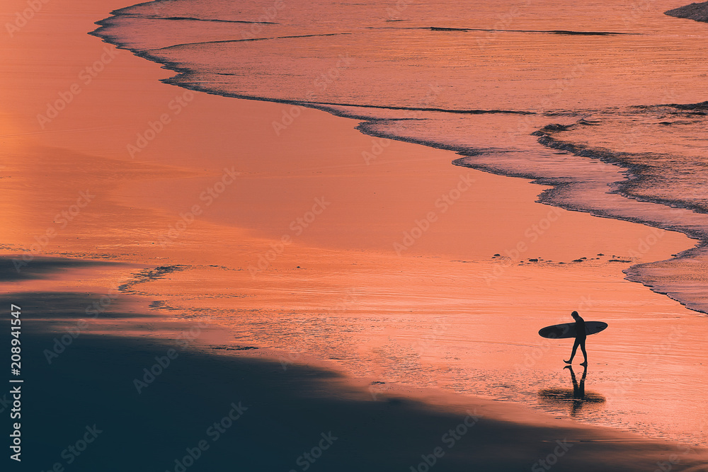 distant surfer silhouette in the shore at sunset - obrazy, fototapety, plakaty 
