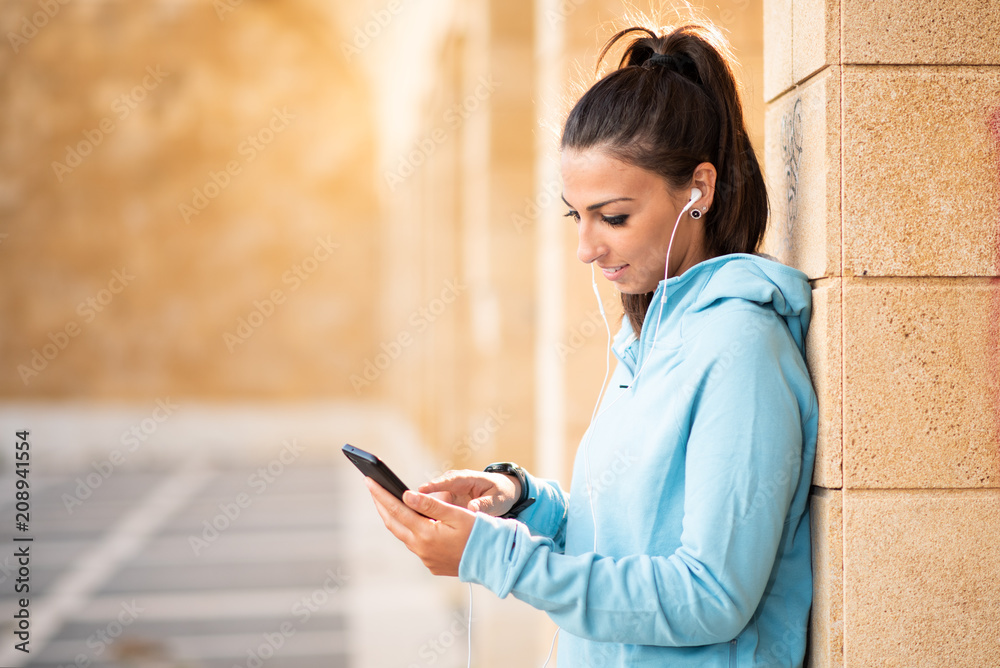 Young female brunette standing with cell phone and head set with hair pulled back Young female brunette standing with cell phone and head set with hair pulled back