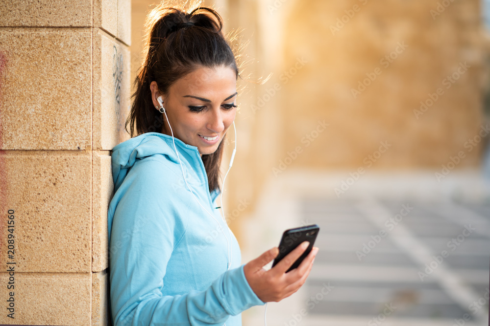 Young female brunette standing with cell phone and head set with hair pulled back Young female brunette standing with cell phone and head set with hair pulled back