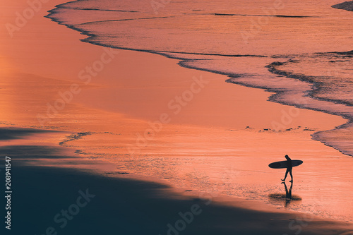 distant surfer silhouette in the shore at sunset
