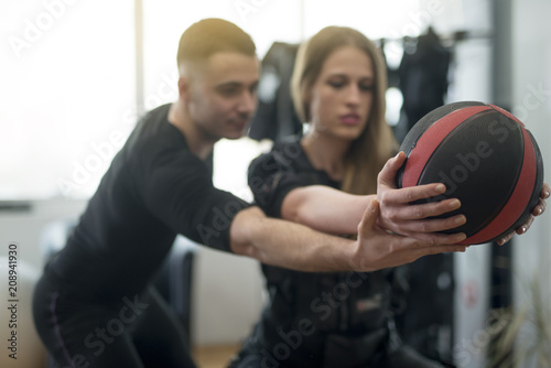Concentrated woman working out ems training with his coach. Personal trainer helps the girl during the exercise © bugarskipavle3