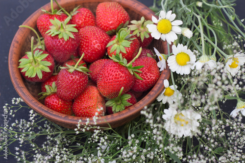 Fototapeta Naklejka Na Ścianę i Meble -  strawberry in clay cup flowers Gypsophila daisy bouquet on a dark background close-up