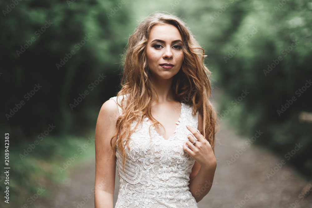 Beautiful bride in elegant white dress holding bouquet posing in park Beautiful bride in elegant white dress holding bouquet posing in park