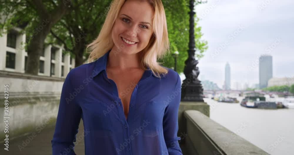 Happy young Caucasian female in blue buttoned shirt posing for camera outdoors, Confident charming young blonde female looking at camera outside near city, 4k Happy young Caucasian female in blue buttoned shirt posing for camera outdoors, Confident charming young blonde female looking at camera outside near city, 4k