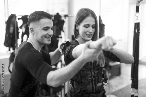 Concentrated woman working out ems training with his coach. Personal trainer helps the girl during the exercise © bugarskipavle3