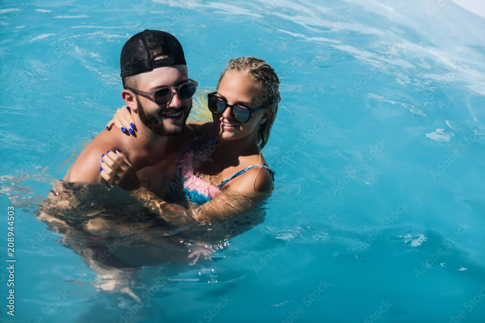 A young Couple is swimming in the pool and laughing A young Couple is swimming in the pool and laughing