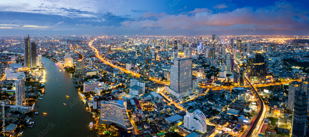 Fototapeta premium Aerial view of Bangkok skyline and skyscraper with BTS skytrain Bangkok downtown. Panorama of Sathorn and Silom business district Bangkok Thailand at night.