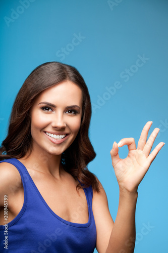 Woman showing okay gesture, over blue