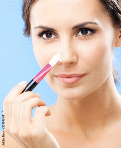 Woman with cosmetics brush, on blue