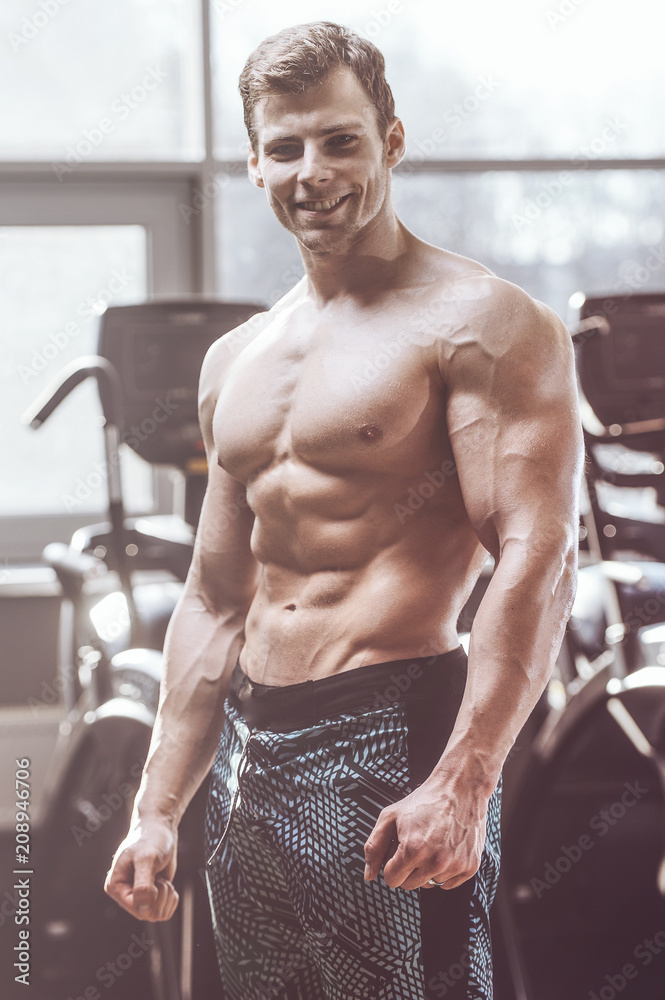 Obraz premium handsome strong bodybuilder athletic men pumping up muscles with dumbbells