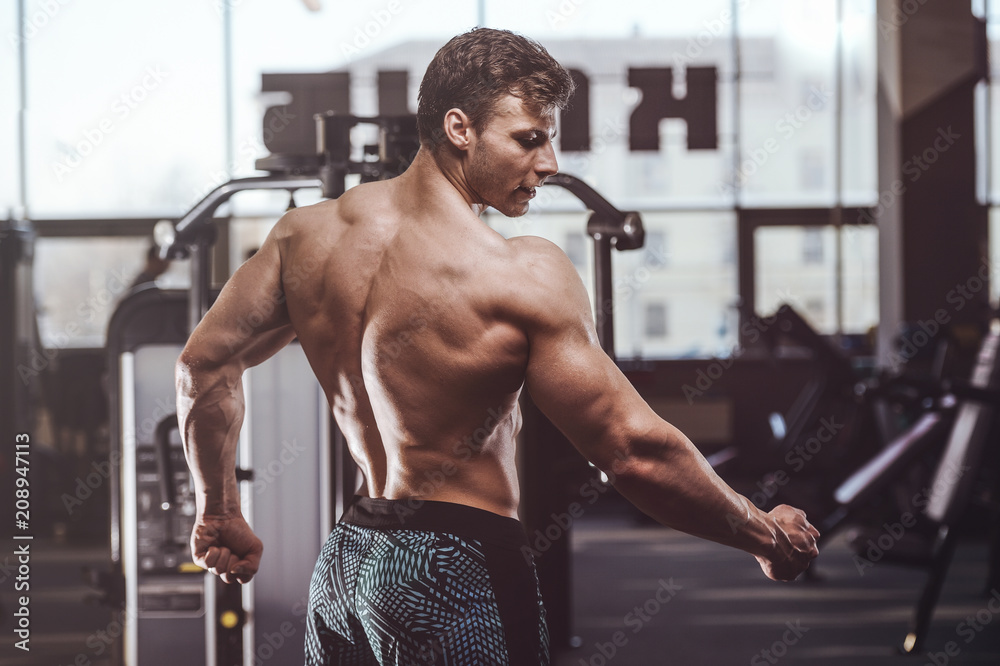Obraz premium handsome strong bodybuilder athletic men pumping up muscles with dumbbells