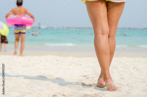 beautiful woman in swimming suit or bikini standing on the beach at the sea on summer holiday day with people go to swimming relaxation activity on the vacation day.