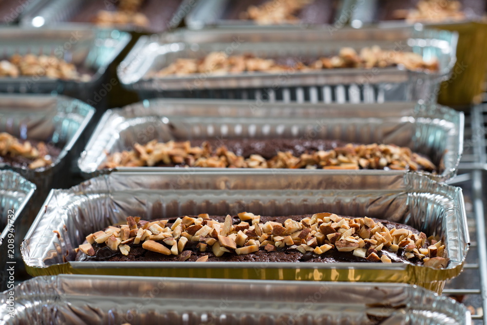 Chocolate cake with almond topping in aluminum foil box packaging.