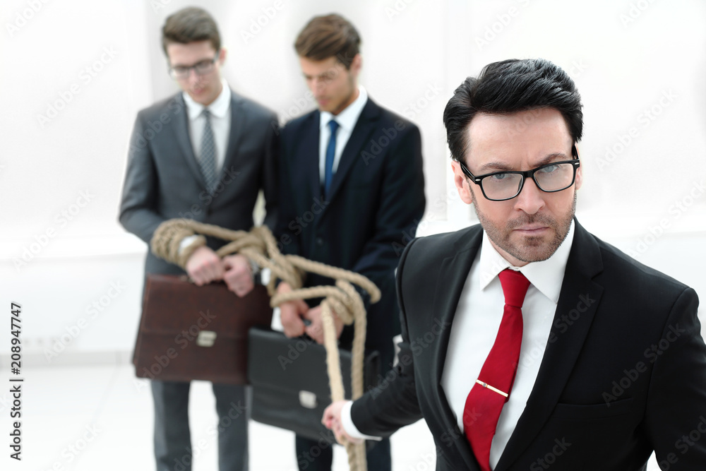 close up. serious businessman pulls business partners tied with a rope close up. serious businessman pulls business partners tied with a rope