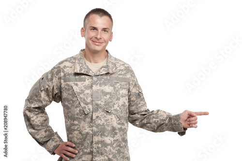 Cuadro en lienzo Army Soldier Smiling and Pointing on Studio White Background
