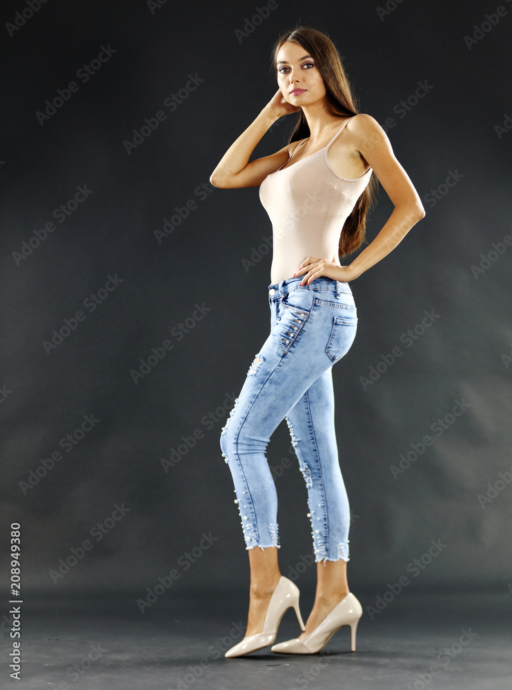 slim young woman in jeans and mood dark background. 