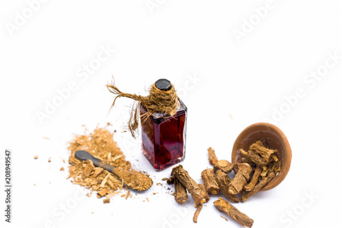 Dark red colored essence of nannari or Indian sarsaparilla in a transparent bottle isolated on white. photo