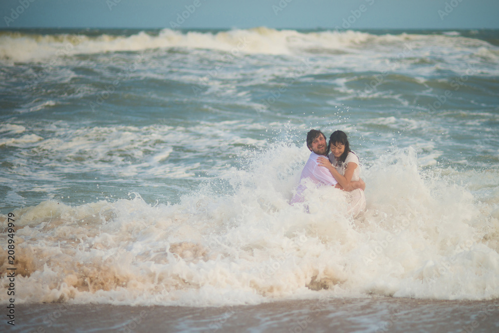 The wave swept the newlyweds. Bride and groom posing in the sea The wave swept the newlyweds. Bride and groom posing in the sea