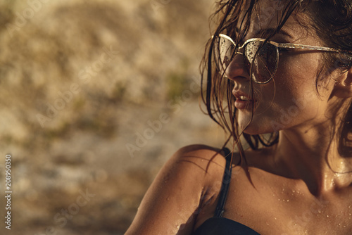 Tanned girl on the sand in sun glass with wet hair. photo