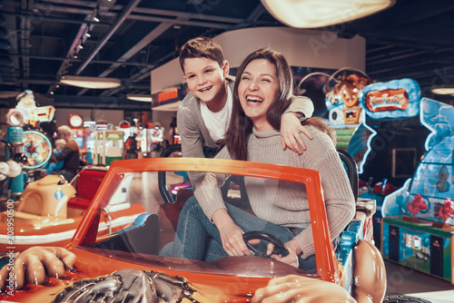 Happy mom and son sitting on toy car photo