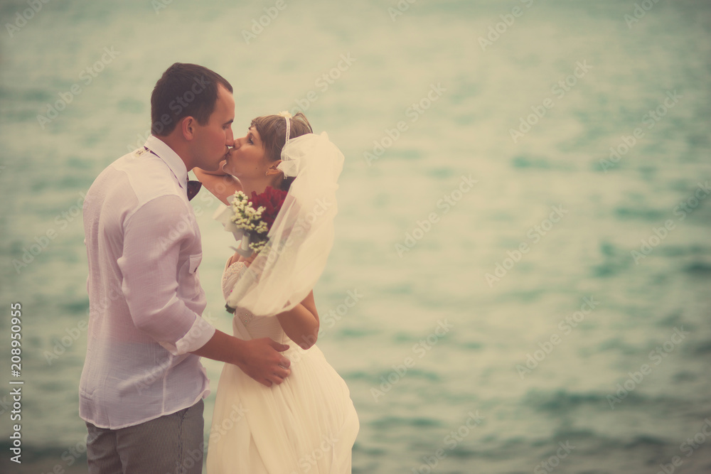 The bride and groom kissing in the background of the sea The bride and groom kissing in the background of the sea