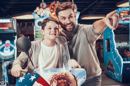 Father and son on toy motorcycle looking forward photo