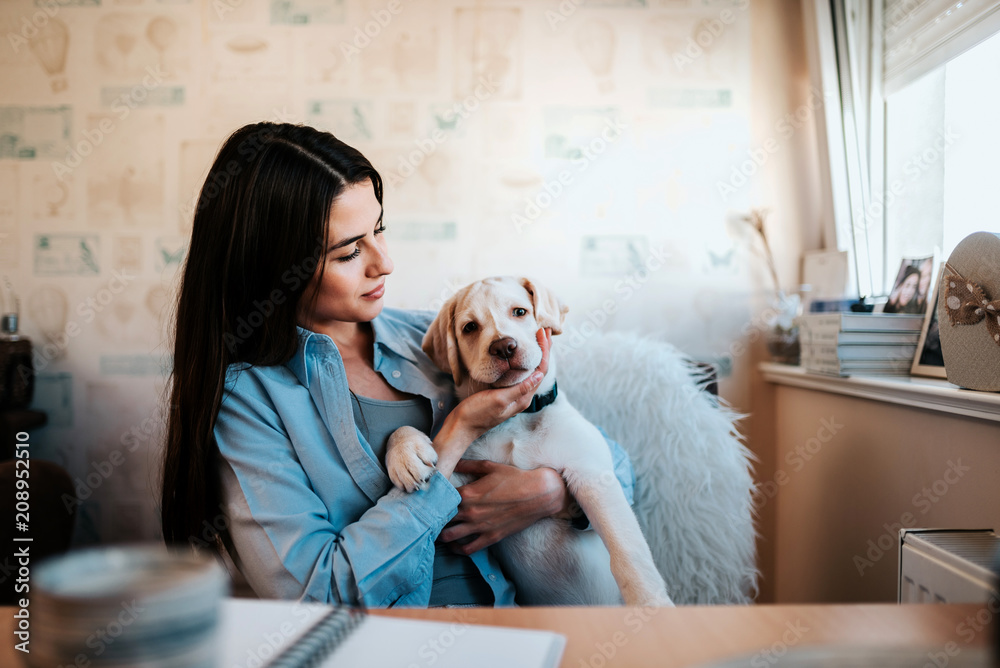 Attractive young woman sitting with her dog by the desk. Attractive young woman sitting with her dog by the desk.