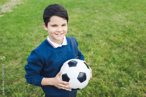 happy kid holding soccer ball and looking at camera on grass field © LIGHTFIELD STUDIOS