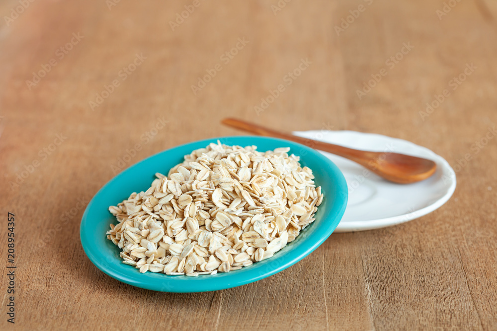 Oats flakes in dish on wood table Oats flakes in dish on wood table