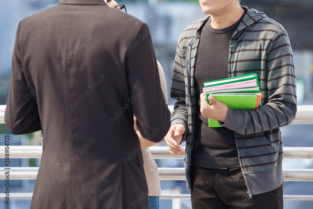 Businessman and college students discussing education on outdoor background Businessman and college students discussing education on outdoor background